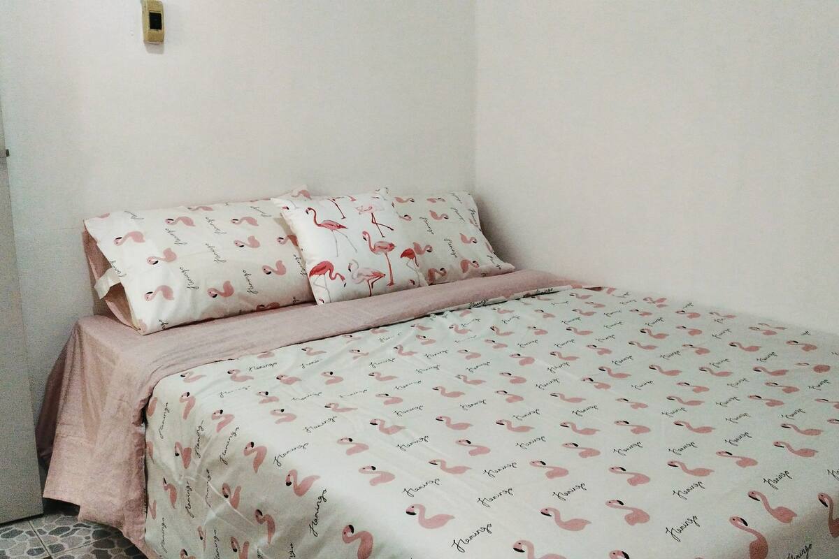 Un dormitorio con cama, una puerta y un interruptor de luz instalado en la pared.