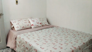 A bedroom with a bed, a door, and a wall-mounted light switch. - Tamada House (Chiang Mai)
