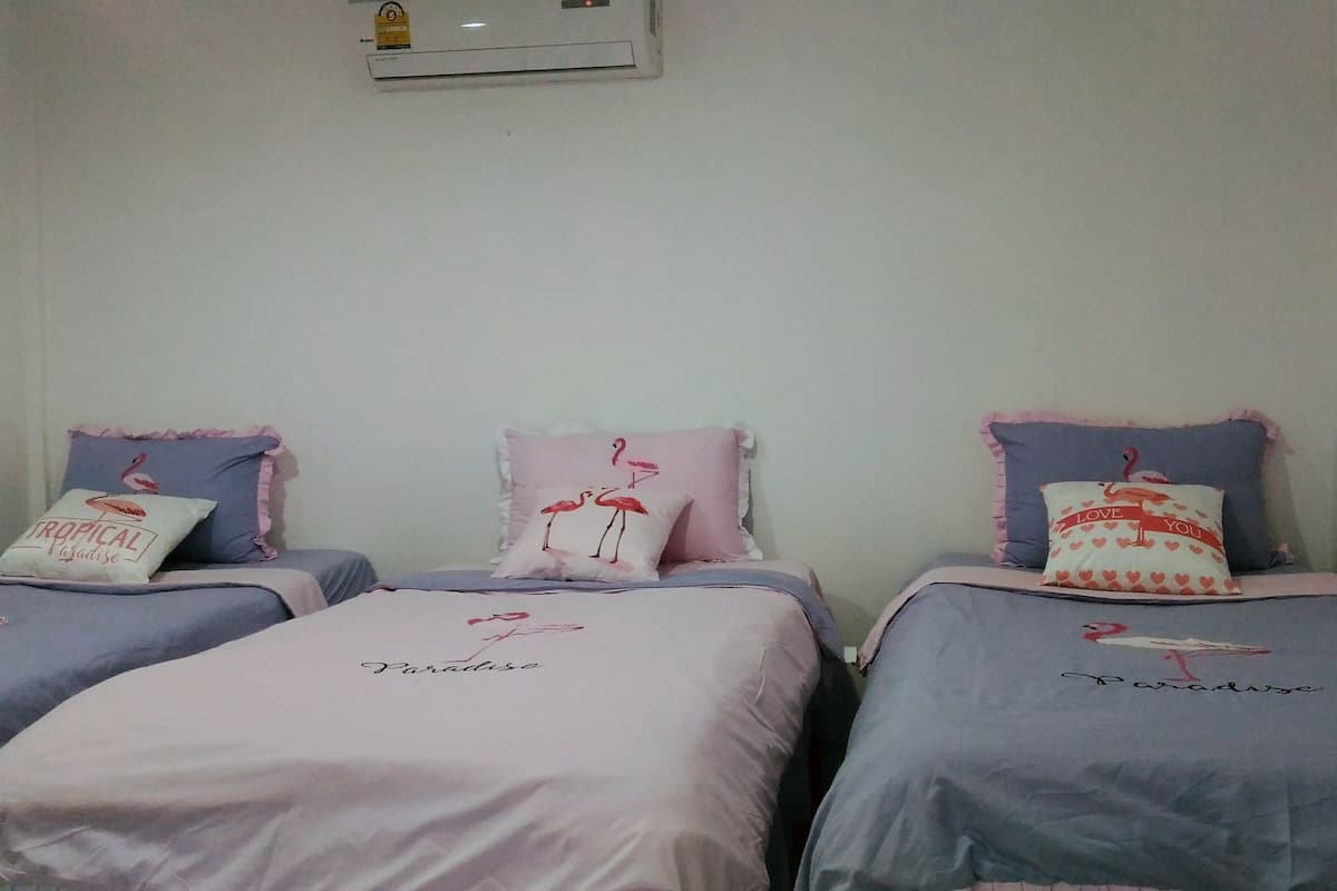 Una habitación con dos camas, cada una con cubrecamas rosa y azul y almohadas a juego.
