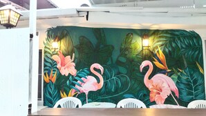 Un mural con flamencos y hojas tropicales.
