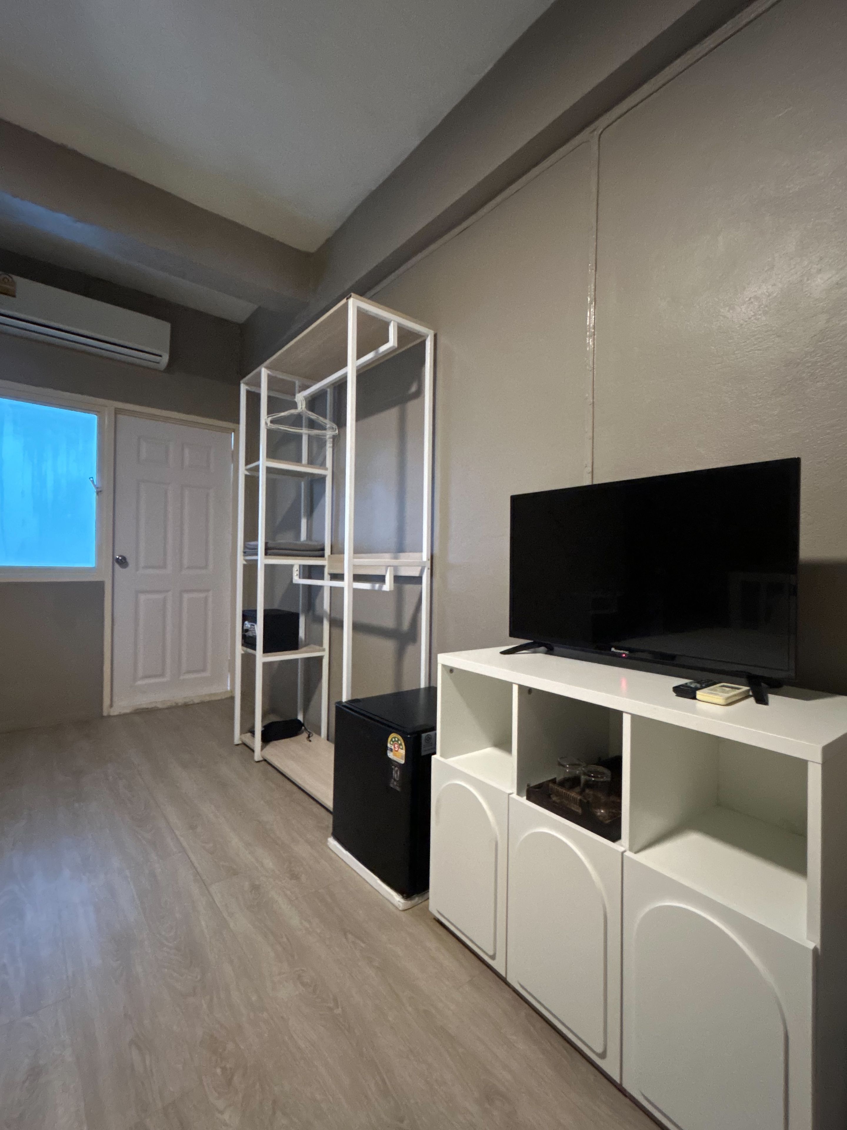Habitació amb un moble blanc d'entreteniment, una televisió negra i un armari blanc amb prestatges.
