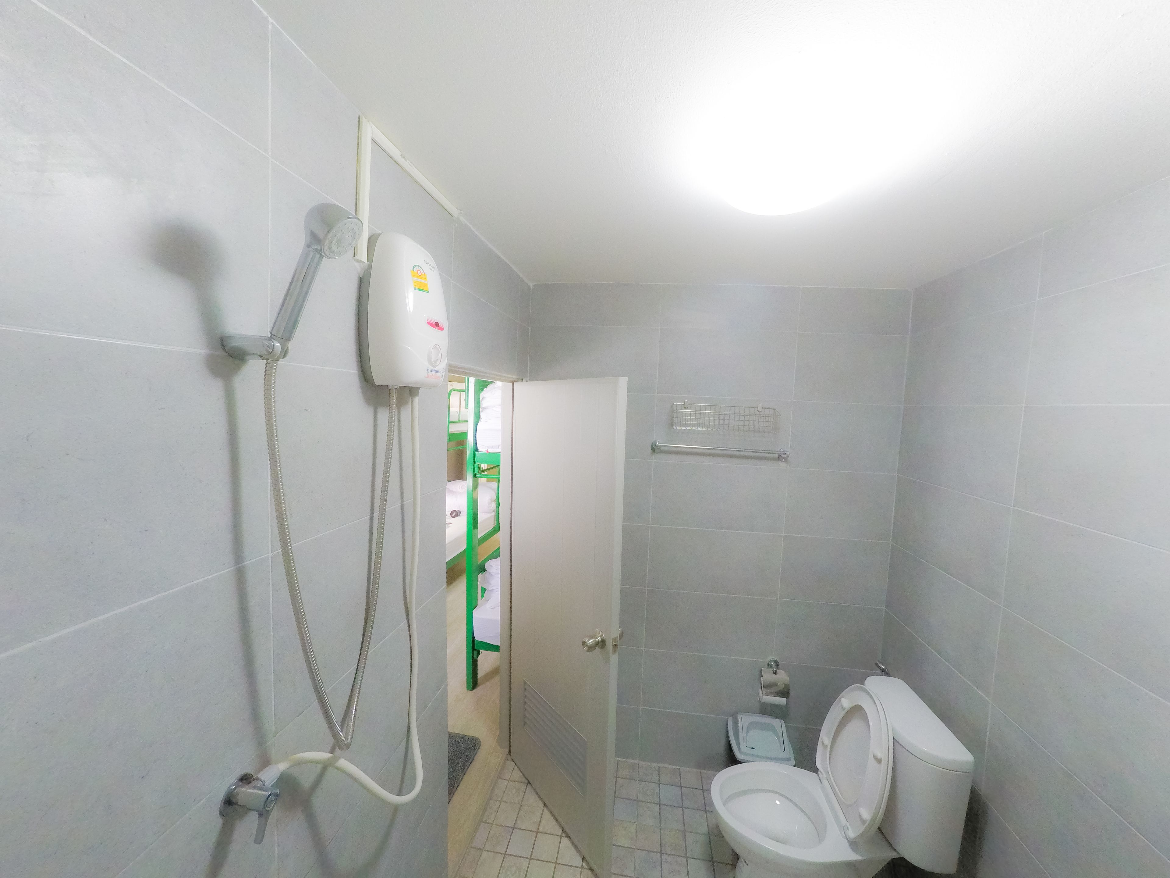 Un baño con inodoro, secamanos y ducha.
