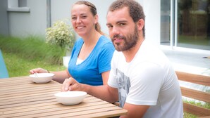 Deux personnes sont assises à une table en bois devant des bols.