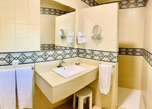 Een badkamer met een wastafel, spiegel en handdoekhouder.