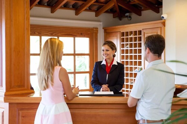 Een receptie met houten lambrisering, een receptiebalie en uitzicht door een raam.