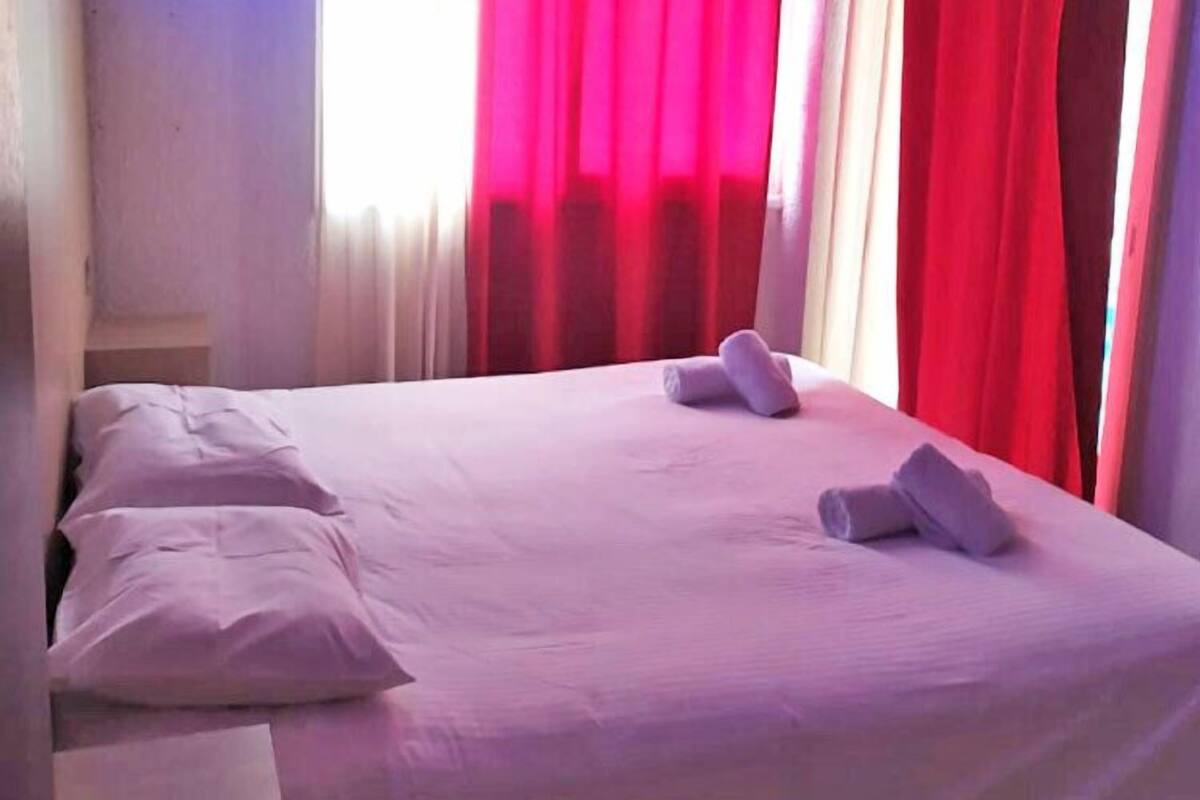 A neatly made bed with white linens and two towels folded on it.