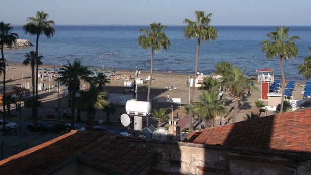 A beach with palm trees, umbrellas, and a lifeguard tower. - Palm Sea Hotel Apartments 2 (Larnaca)