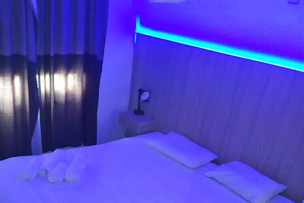 A hotel room with a bed, curtains, and a nightstand with a lamp.