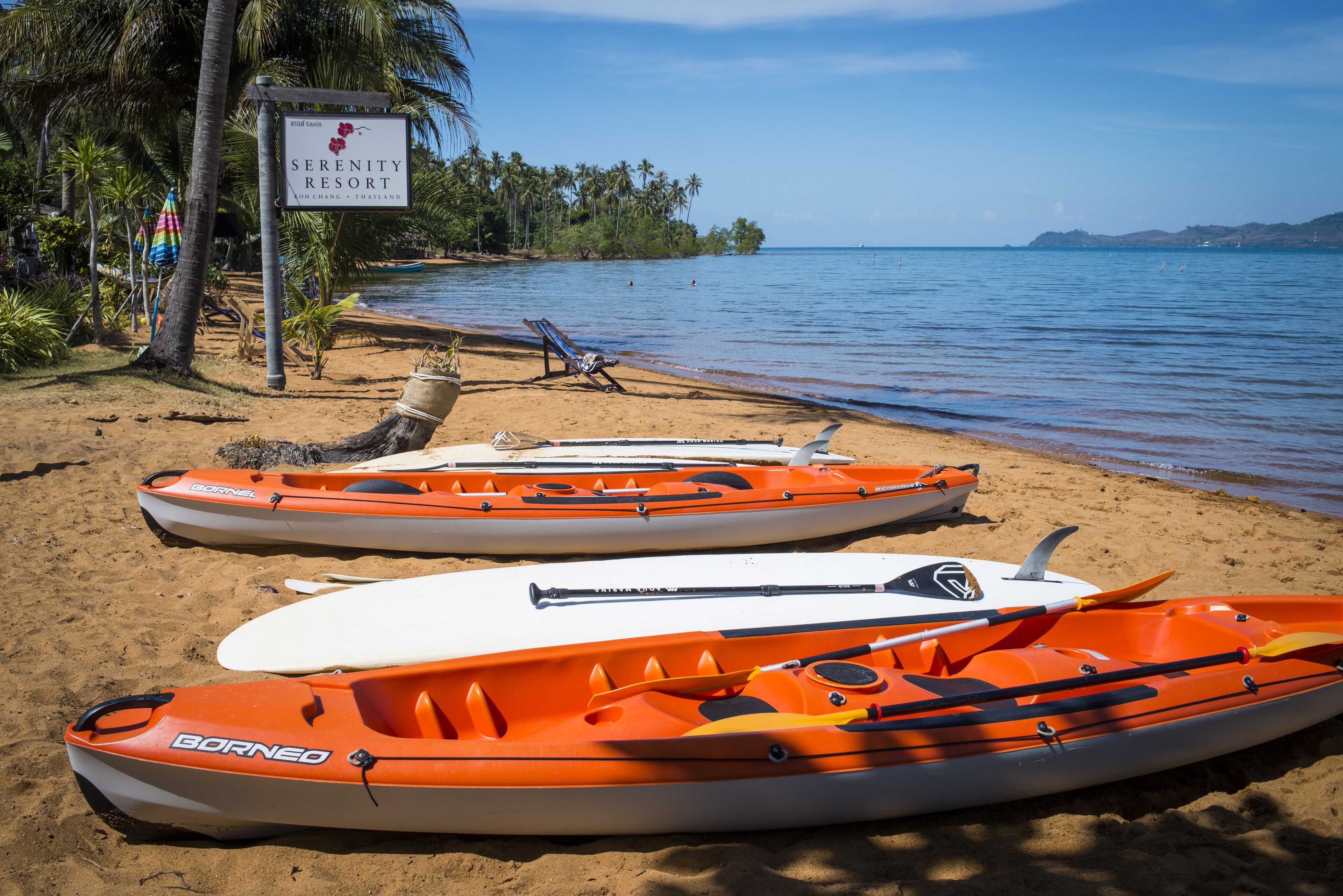 Kayaks on a beach with a sign for Serenity Resort.