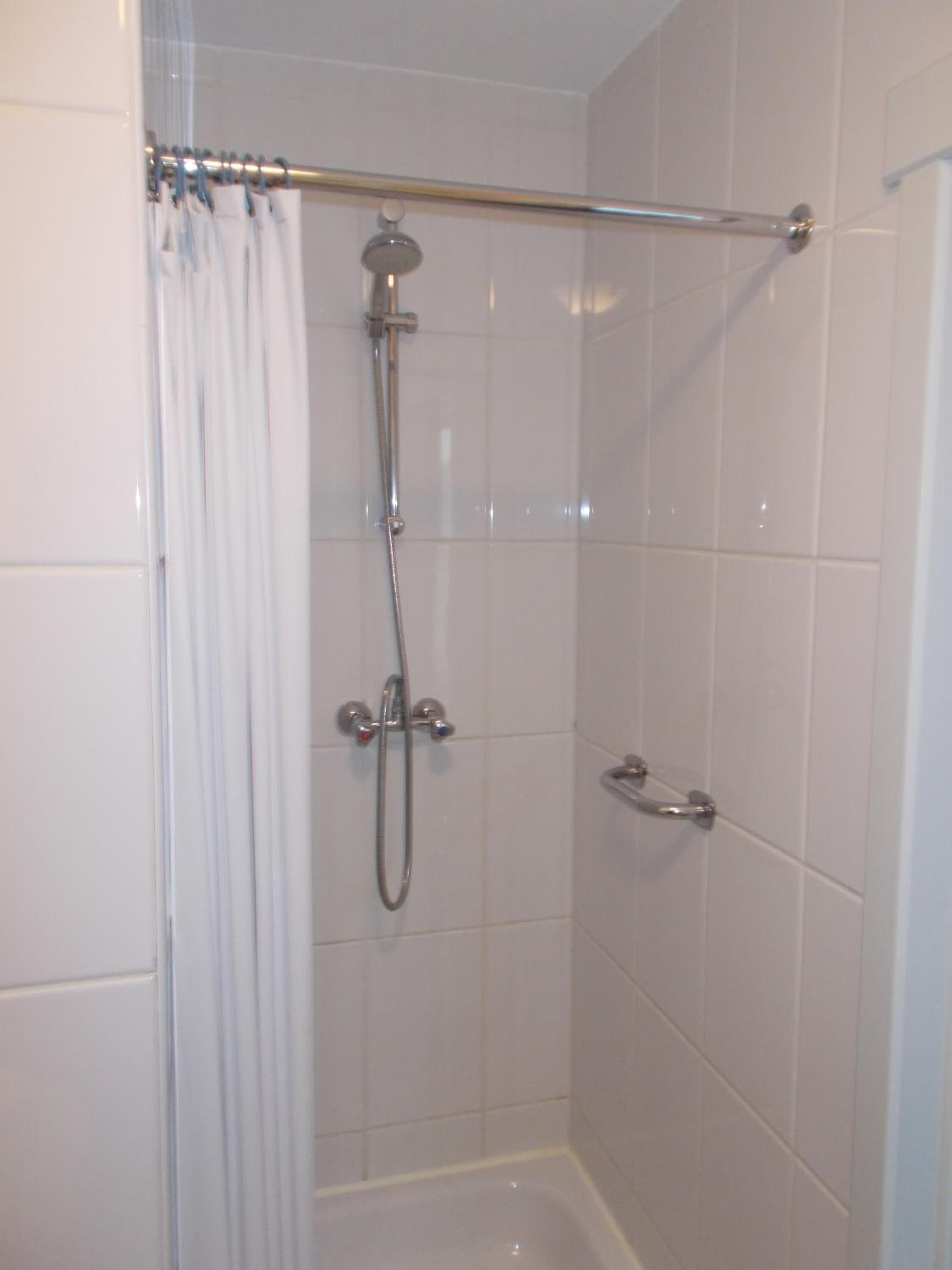 A shower with a handheld showerhead and a handheld faucet.