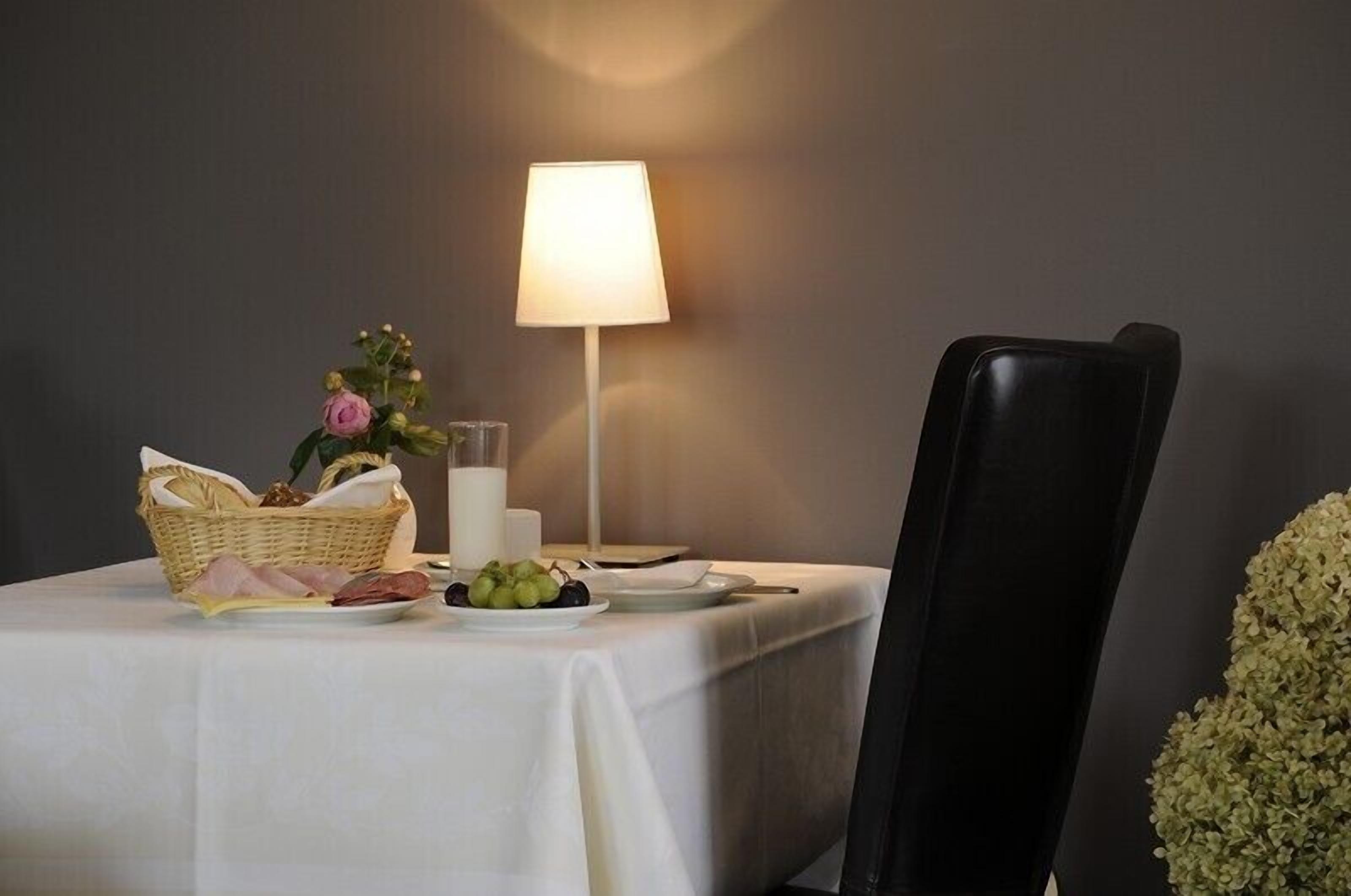 Een eettafel gedekt met een broodmand, een bord druiven, een kaars en een vaas met bloemen.