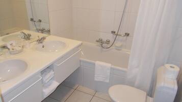 A bathroom with two sinks, a bathtub, and a toilet.