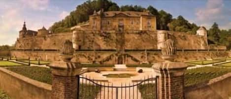 A historic building with a central courtyard, surrounded by a high wall and a gate.