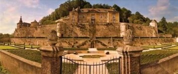 Um edifício histórico com um pátio central, rodeado por um muro alto e um portão.