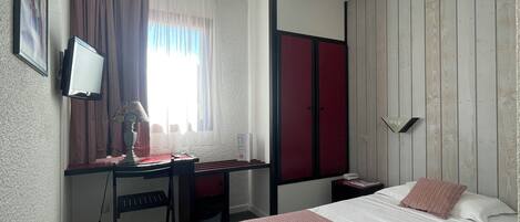 Una habitación de hotel con cama, escritorio y televisor.