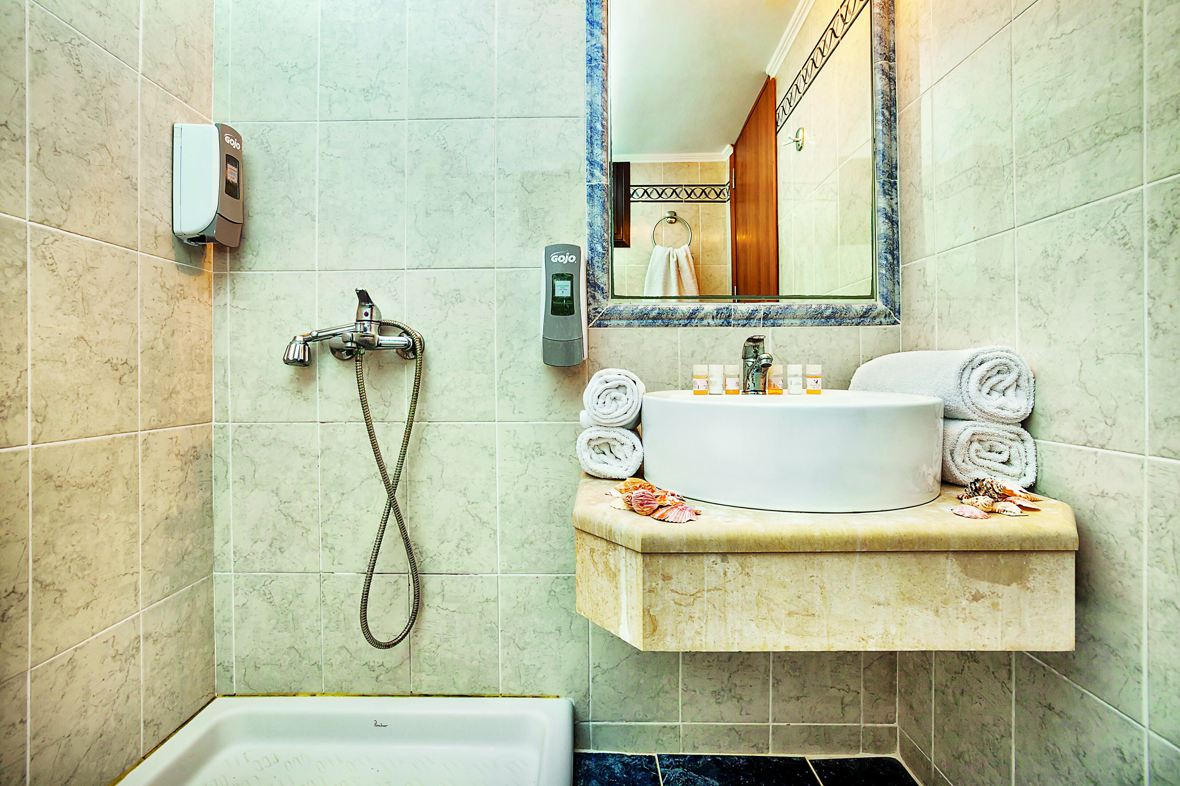 Un baño con bañera, lavamanos con toallas y espejo.