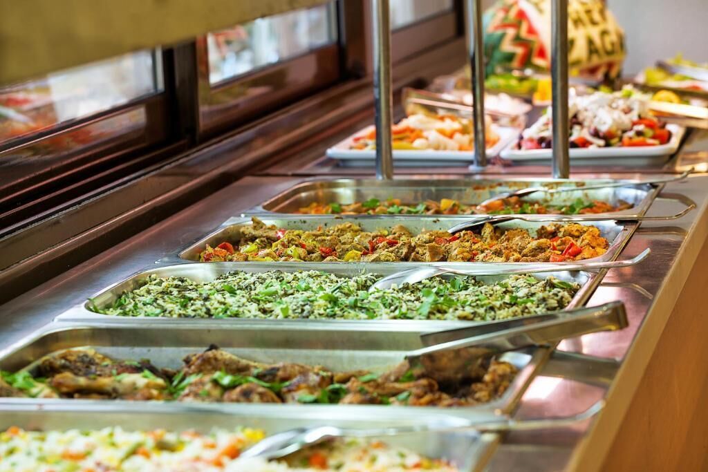 A buffet with various dishes including salads, meats, and rice.
