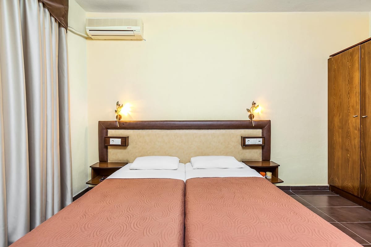 Habitación de hotel con cama doble, dos mesitas de noche con lámparas, aire acondicionado y un armario.