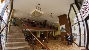 A hotel lobby with a staircase, seating areas, and a view through a glass wall. - Hotel Cisar (Lviv)