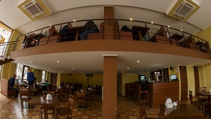 A spacious restaurant with a central open area, multiple dining tables, and a mezzanine level with seating. - Hotel Cisar (Lviv)