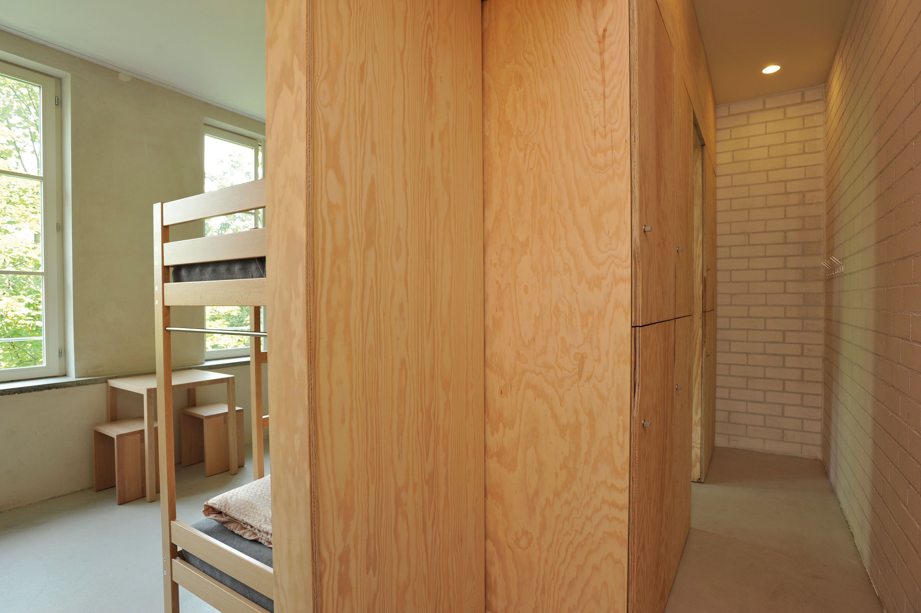 A room with a bunk bed, a wooden desk, and a brick wall.