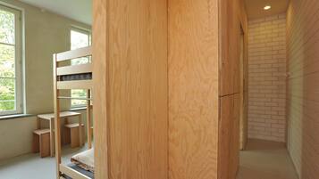 A room with a bunk bed, a wooden desk, and a brick wall.