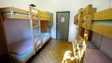 Ein Schlafsaalzimmer mit Etagenbetten, einer Tür und einer weißen Ziegelwand.
