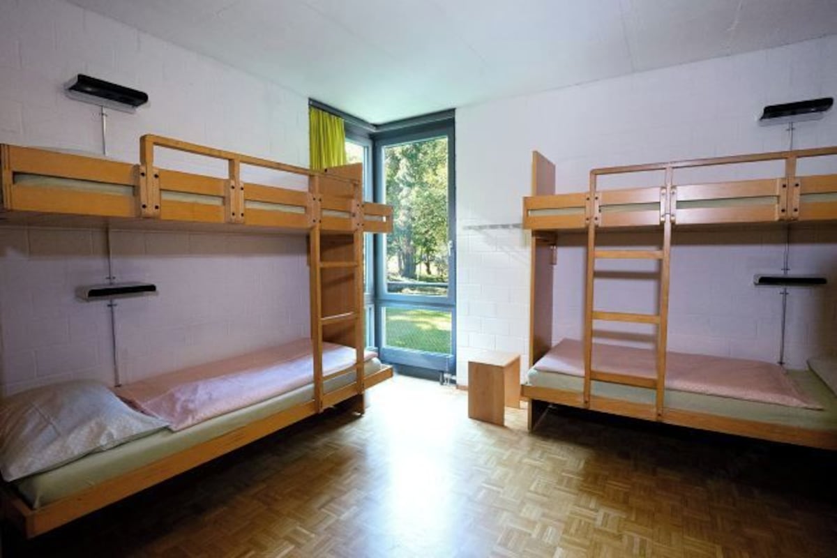 Ein Schlafraum mit Etagenbetten, einem Fenster und einem kleinen Tisch.