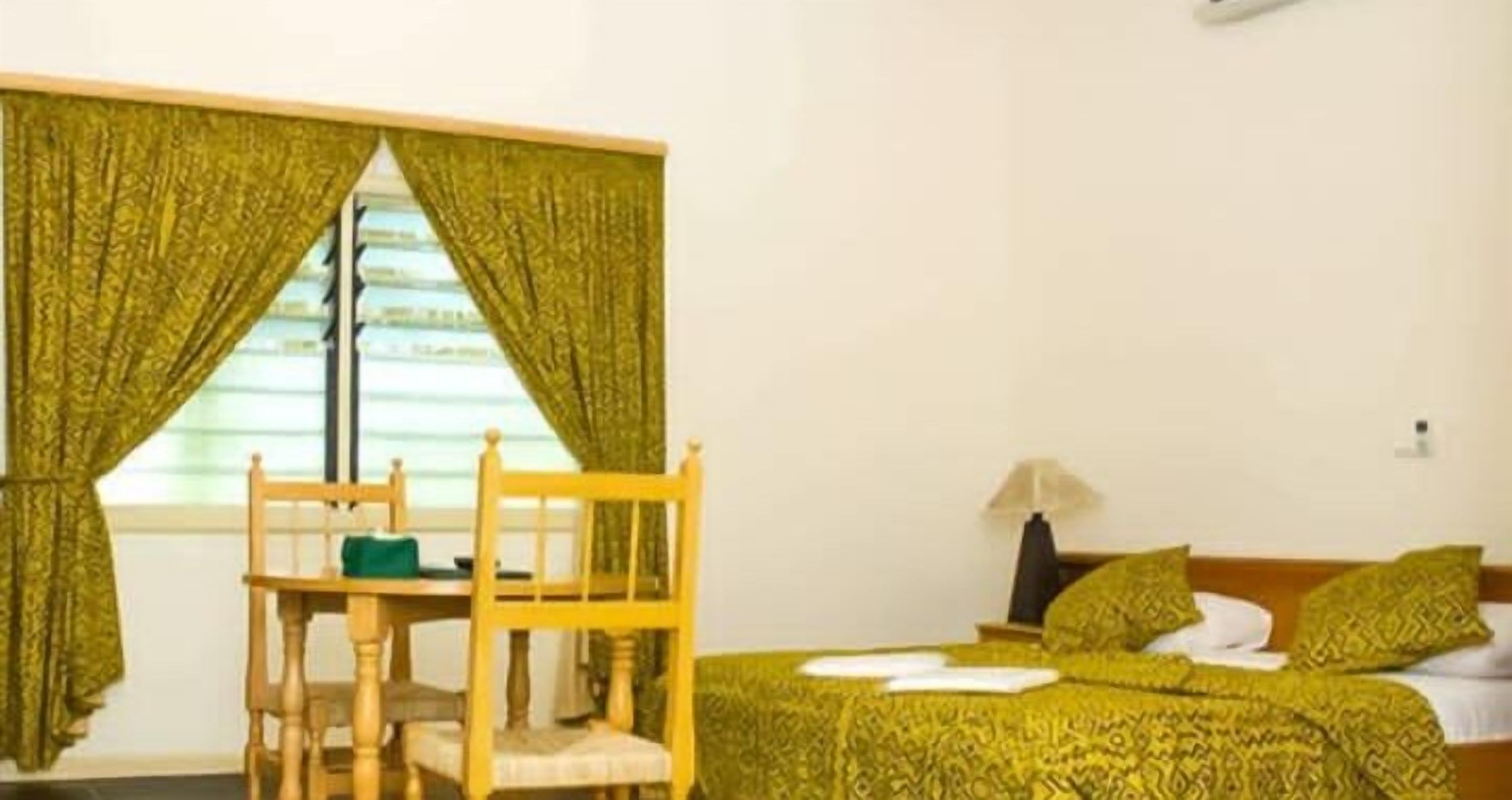A room with a bed, a chair, a table, and a window with curtains.