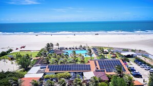 A resort with a swimming pool, solar panels, and a beach view. - Hotel Vila Jardim (Beberibe)