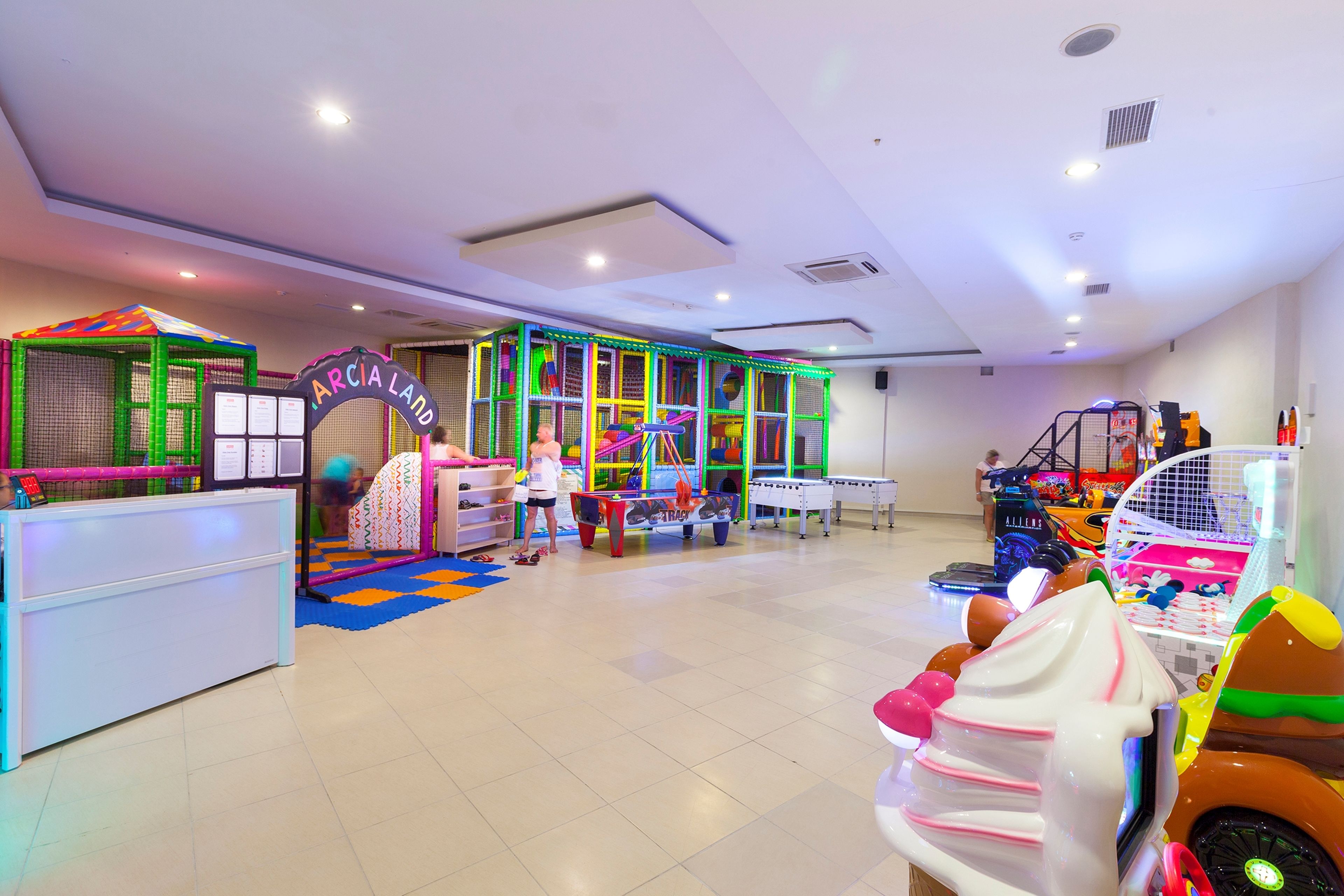 Zona de juegos infantiles con estructuras coloridas y un mostrador de recepción.