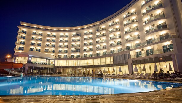 A large hotel with multiple balconies, a swimming pool, and a covered area with lounge chairs. - Narcia Resort Side - All Inclusive (Manavgat)