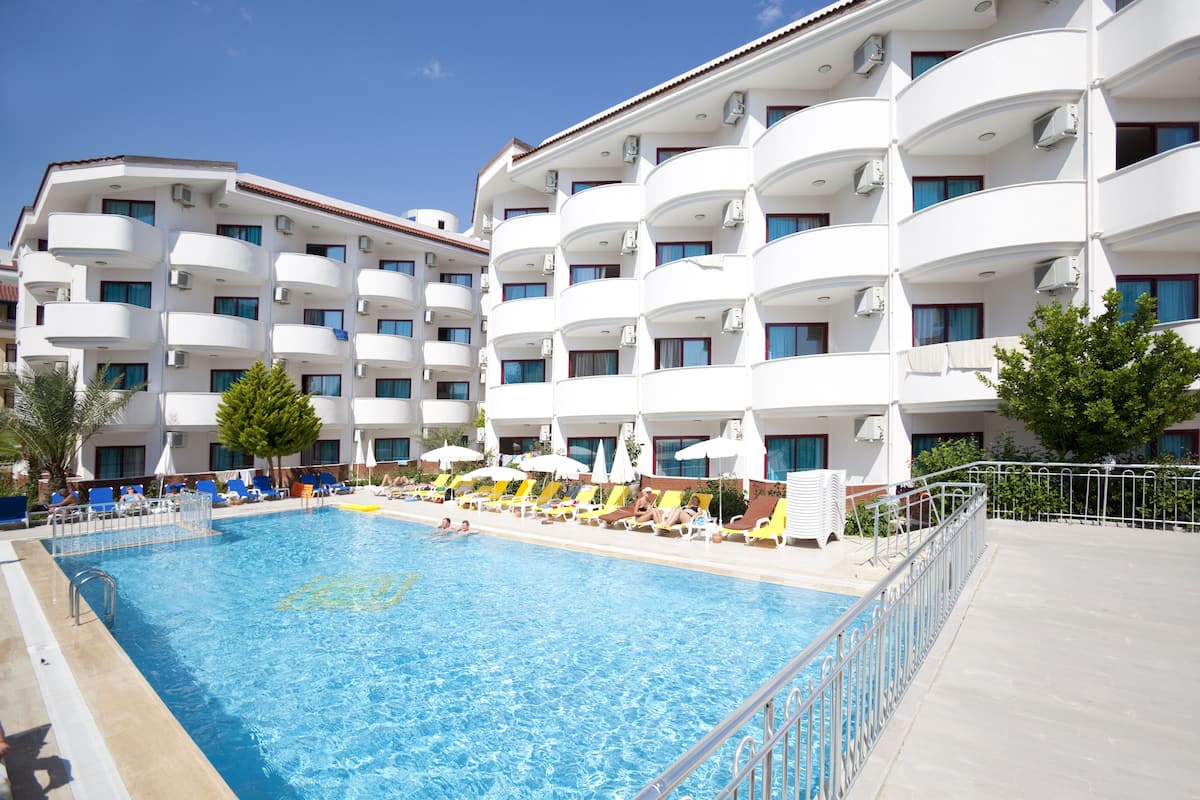 Un hotel con piscina, varios balcones y sillas de sol.