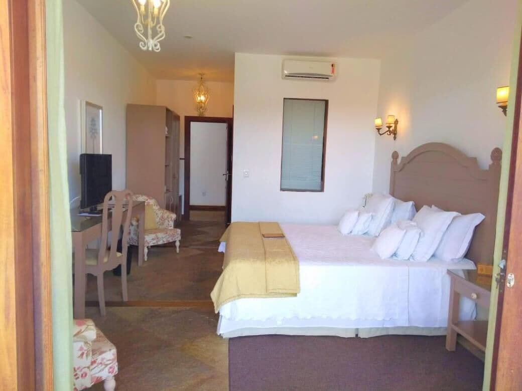 A hotel room with a bed, a desk, a chair, and a television.