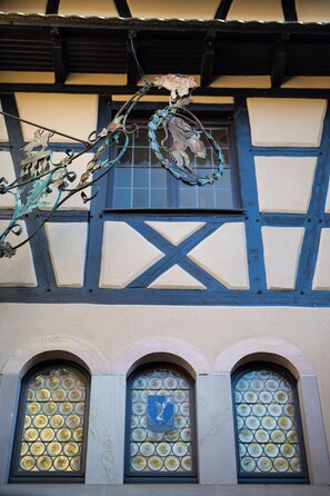 A building with a half-timbered facade, arched windows, and a decorative metal piece above the windows.