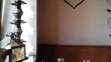 A dining table with wine glasses and a candle, a lamp, and a decorative wall with a floral design.