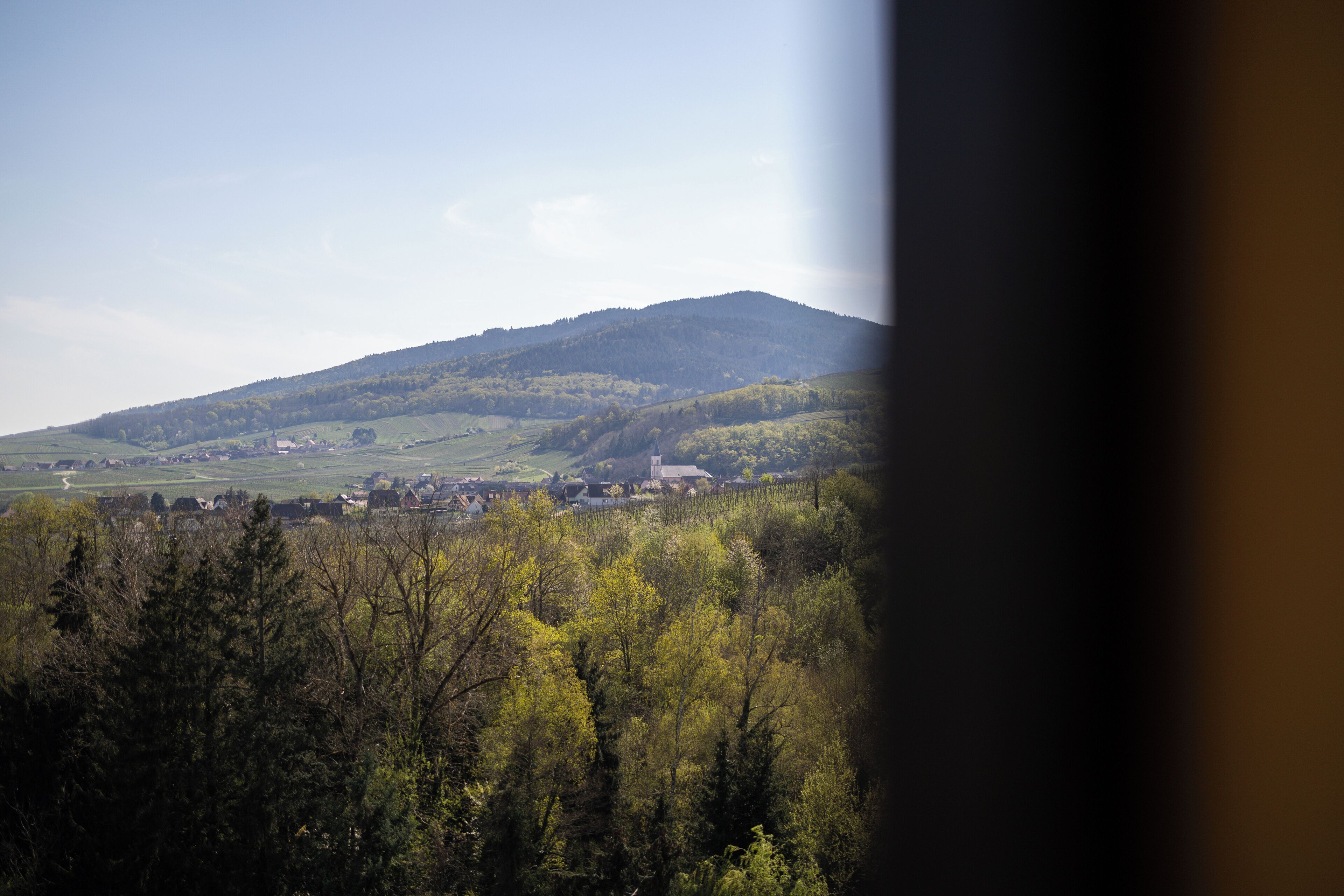 Vista de un pueblo situado en un valle, con una colina destacada al fondo.