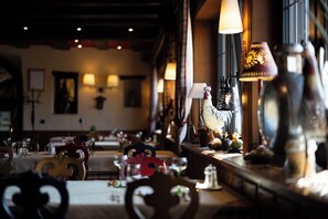 A restaurant interior with tables set for dining, a decorative rooster, and warm lighting.