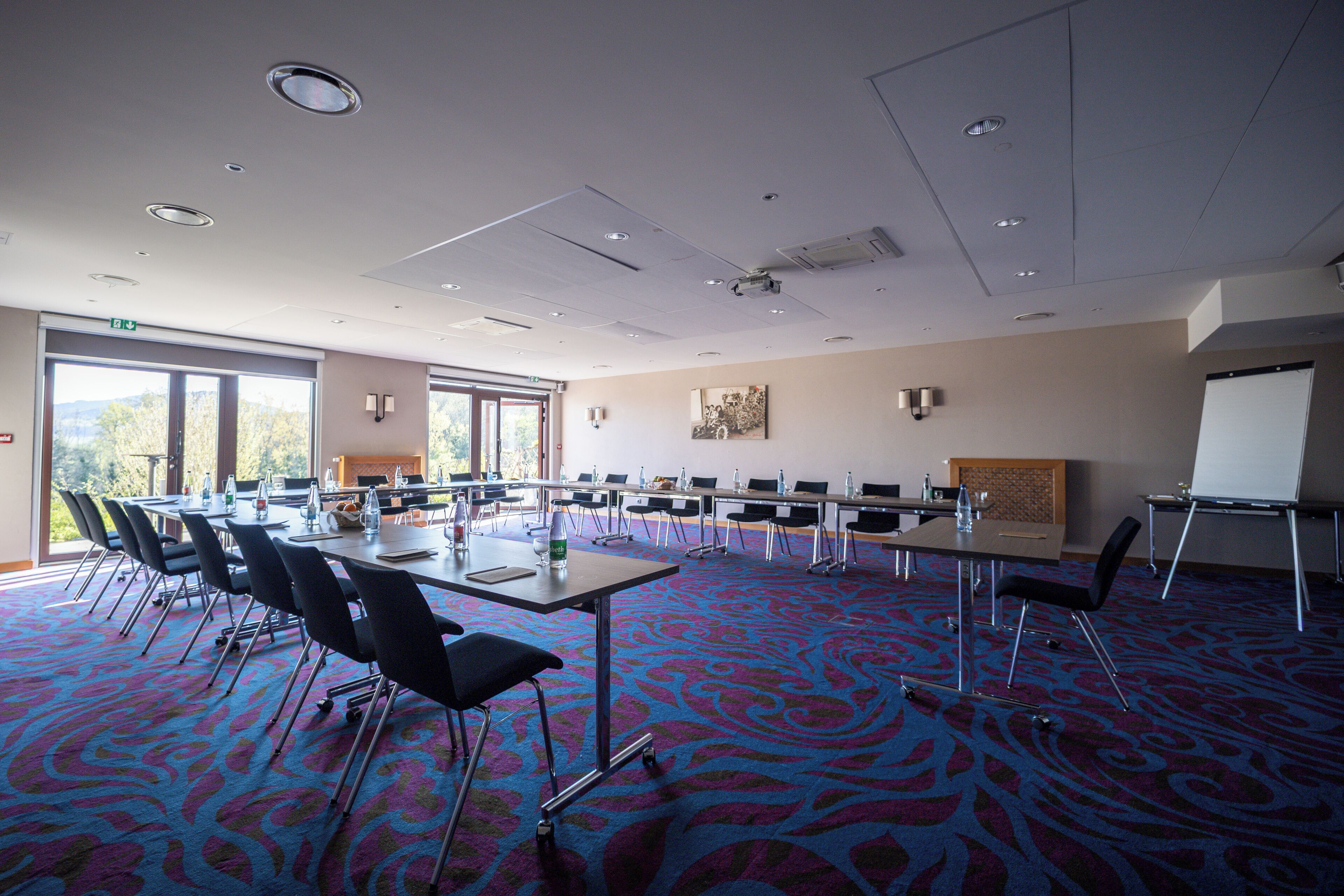 Une salle de conférence avec une longue table, des chaises et un tableau blanc.