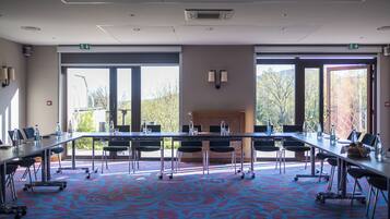 A conference room with a large table, chairs, and a patterned carpet.