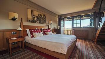 A large bed with a wooden headboard, a nightstand with a lamp, and a red-striped carpet.