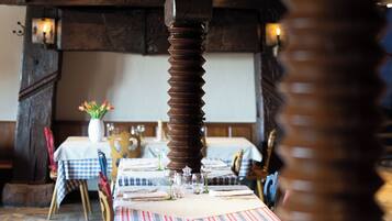 Un restaurante con vigas de madera y mantel a cuadros. Las mesas están dispuestas con platos, vasos y cubiertos.