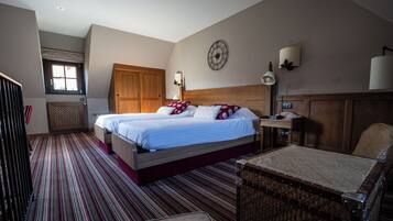 Habitación de hotel con dos camas, un escritorio, una silla, un reloj en la pared y una ventana con vistas.