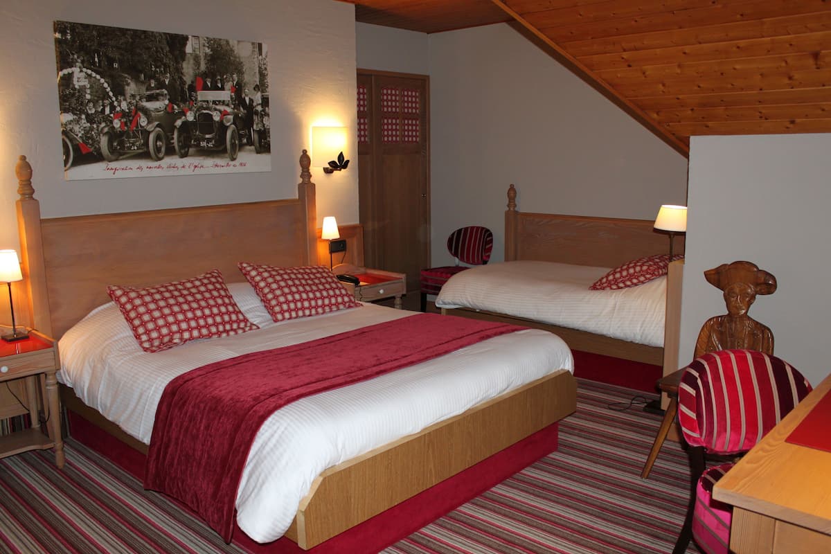 A hotel room with two beds, a wooden ceiling, a wall-mounted picture, and a wooden statue.