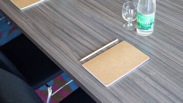 Mesa de conferência com duas garrafas de água, dois copos e dois blocos de anotações.