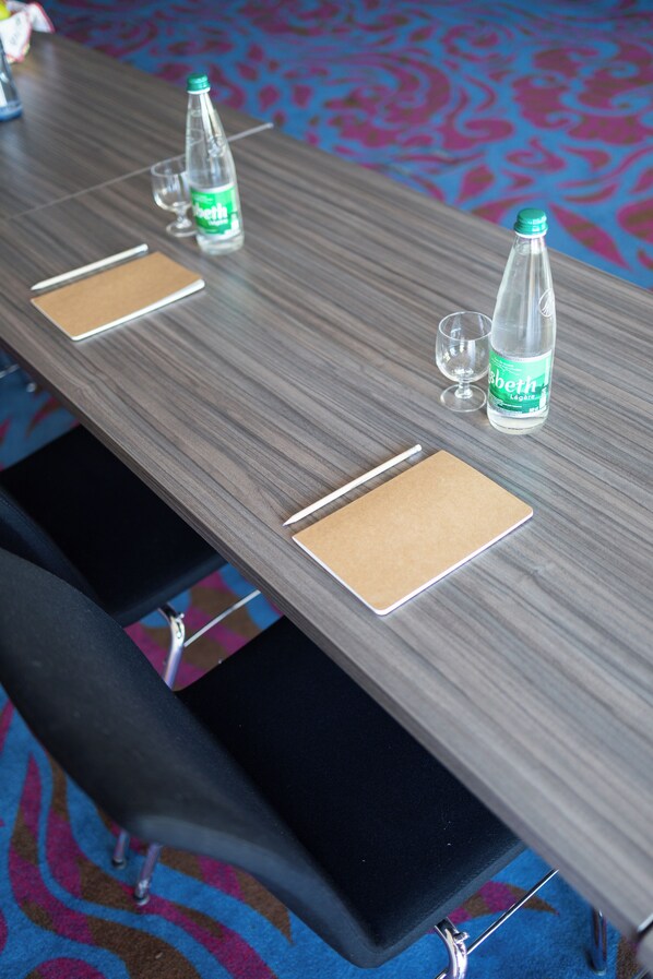 Mesa de conferência com duas garrafas de água, dois copos e dois blocos de anotações.