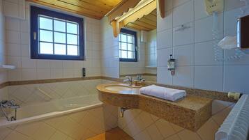 A bathroom with a bathtub, a sink, a mirror, and a window.