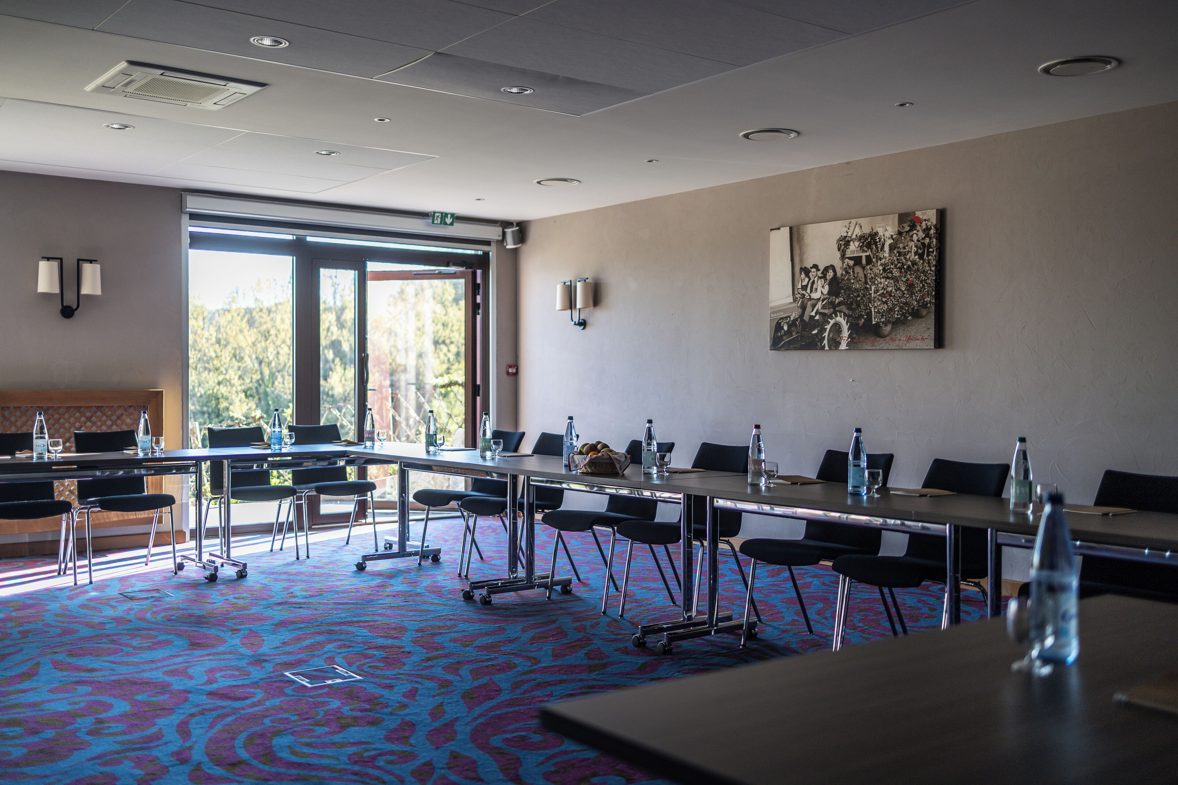A conference room with a large table, chairs, and a carpeted floor.