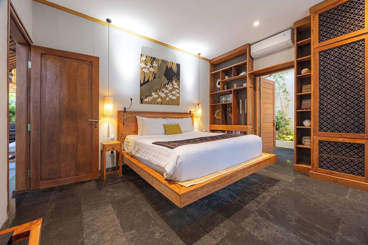 Ein geräumiges Schlafzimmer mit einem großen Bett, einem Holzkopfende und einem eingebauten Bücherregal.