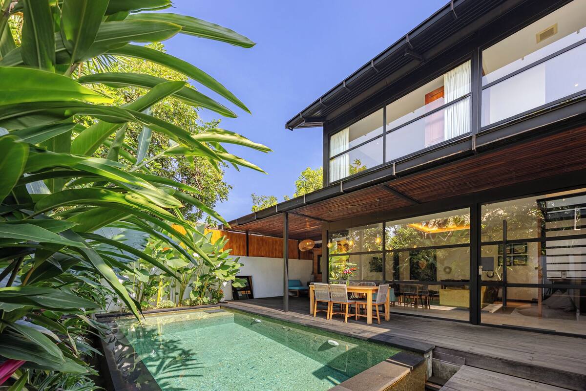 Ein modernes Haus mit Swimmingpool, Holzterrasse und großen Fenstern.